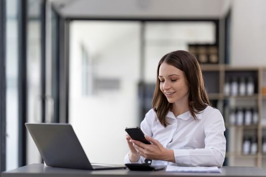 Business woman using smartphone for do math finance on wooden desk in office, tax, accounting, financial concept.