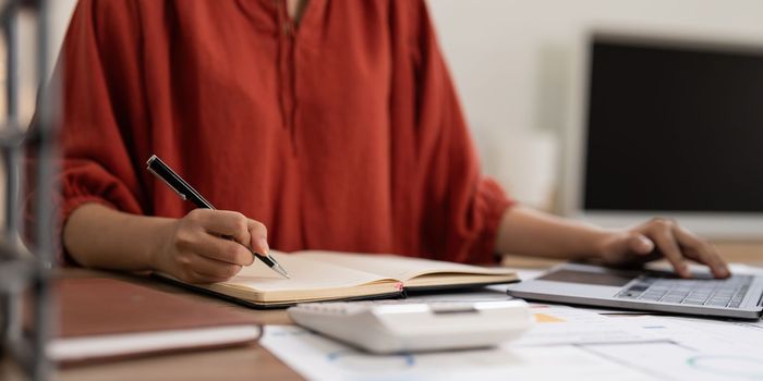 Asian Business woman writing saving account balance with working at home, account and saving concept.