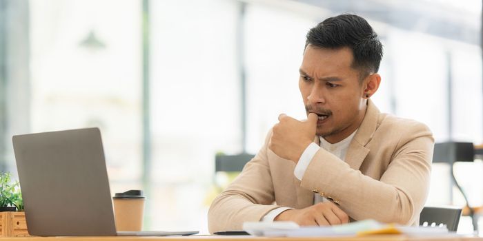 Stressed Asian businessman worry with many document on desk at office.