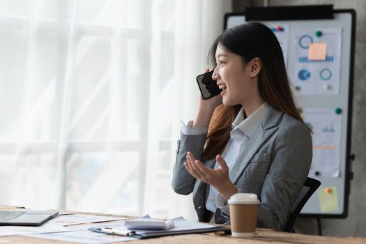 Beautiful asian businesswoman working with cell phone in office. business finance concept.