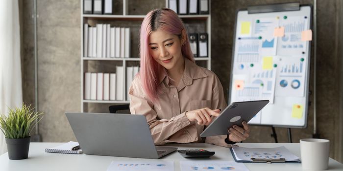 Asian Business woman working to analyze technical price graph and indicator with business team talking by cell phone. account or saving money or insurance concept.