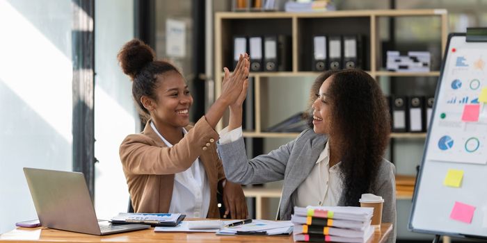 Two black business woman celebrate when business goal success. Achievement and Business Goal Success Concept.