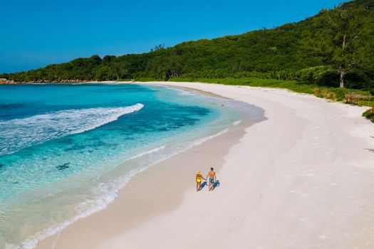 Anse Cocos beach, La Digue Island, Seychelles, Drone aerial view of La Digue Seychelles bird eye view. of tropical Island, couple men, and woman walking at the beach during sunset at a luxury vacation