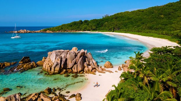 Anse Cocos beach, La Digue Island, Seychelles, Drone aerial view of La Digue Seychelles bird eye view.of tropical Island, couple men, and woman walking at the beach during sunset at a luxury vacation