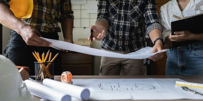 Architect man working with blueprints for architectural plan, engineer sketching a construction project concept.