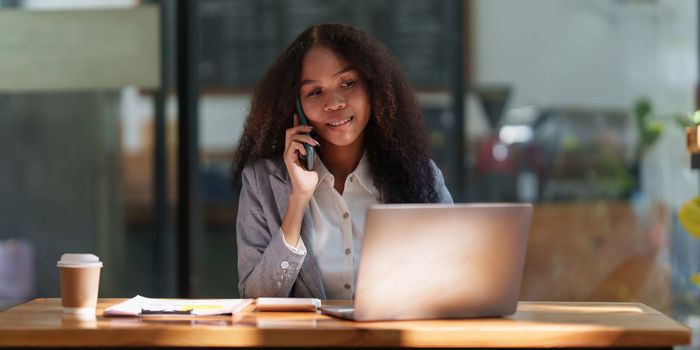 Asian businesswoman talking with client on mobile phone working at office.