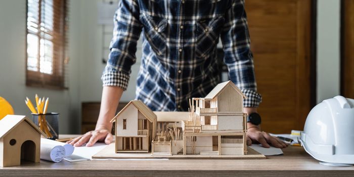 Architect man working with blueprints for architectural plan, engineer sketching a construction project concept.