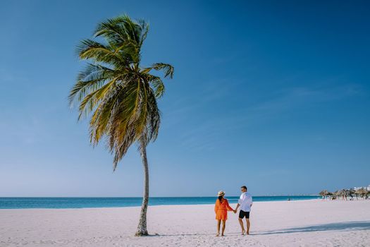 Eagle Beach Aruba, Palm Trees on the shoreline of Eagle Beach in Aruba, couple man, and woman on the beach of Aruba