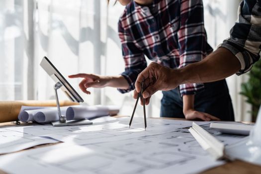 Architect team working with blueprints for architectural plan, engineer sketching a construction project, green energy concept.