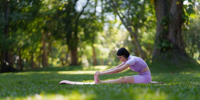 Attractive Asian female in sportswear practicing yoga in the outdoor park.