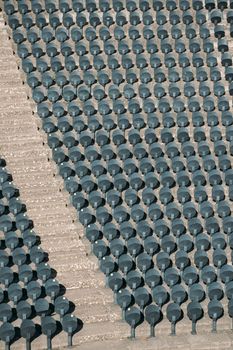 Empty rows of new comfortable plastic chairs attached to floor in an empty stadium. Seat designed for sports arenas. Stone staircase of sports stadium divides chairs into sectors