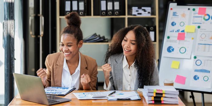 Two black business woman celebrate when business goal success. Achievement and Business Goal Success Concept.