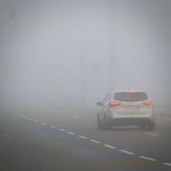 Cars in the fog. Bad winter weather and dangerous automobile traffic on the road. Light vehicles in fog.