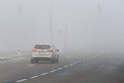 Cars in the fog. Bad winter weather and dangerous automobile traffic on the road. Light vehicles in fog.