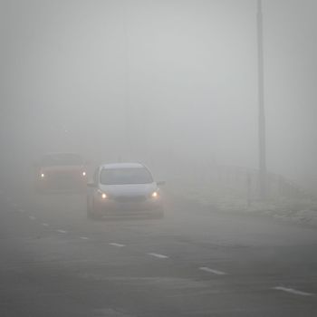 Bad weather driving - foggy hazy country road. Motorway - road traffic. Winter time.