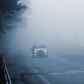 Bad weather driving - foggy hazy country road. Motorway - road traffic. Winter time.