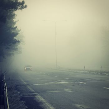 Bad weather driving - foggy hazy country road. Motorway - road traffic. Winter time.