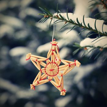 Christmas background with tree and natural old straw decoration. Winter holiday time with snow.