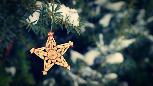 Christmas background with tree and natural old straw decoration. Winter holiday time with snow.