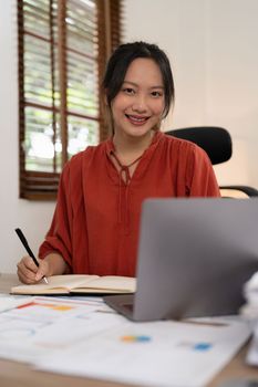 Asian Business woman writing saving account balance with working at home, account and saving concept.