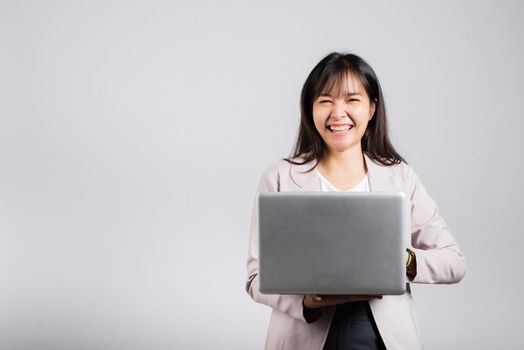 Woman smiling confident smiling holding using laptop computer and typing keyboard for online sending email or chat, Portrait excited happy Asian young female studio shot isolated on white background