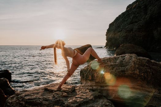 Young woman with black hair, fitness instructor in pink sports leggings and tops, doing pilates on yoga mat with magic pilates ring by the sea on the beach. Female fitness daily yoga concept