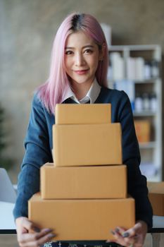 Startup small business entrepreneur of freelance Asian woman using a laptop with box Cheerful success online marketing packaging box and delivery SME idea concept.