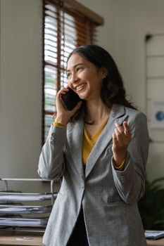 Asian businesswoman talking with client on mobile phone working at office.