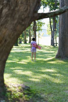 Attractive Asian female in sportswear practicing yoga in the outdoor park.