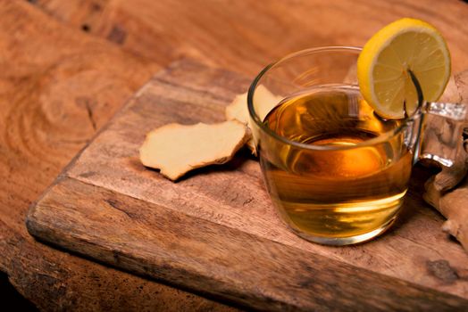 Cup of spiced tea with cinnamon sticks, anise star, lemon and jinger on rustic table