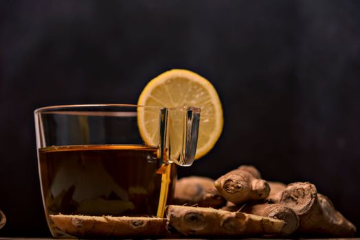 Cup of spiced tea with cinnamon sticks, anise star, lemon and jinger on rustic table