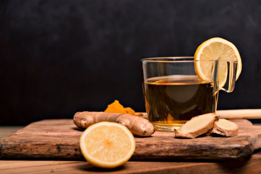 Cup of spiced tea with cinnamon sticks, anise star, lemon and jinger on rustic table