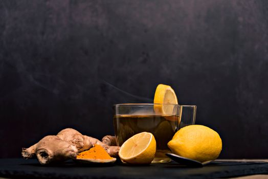 Cup of spiced tea with cinnamon sticks, anise star, lemon and jinger on rustic table