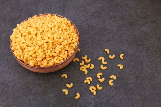 Elbow macaroni on a stone black background