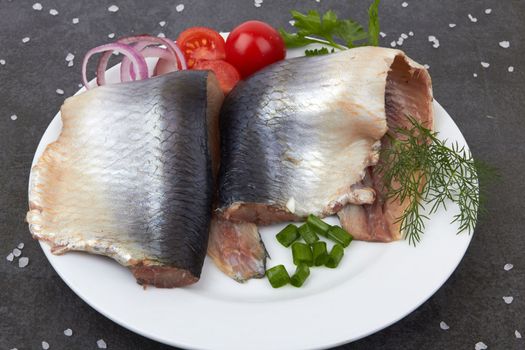 Slices of herring fish on stone black surface
