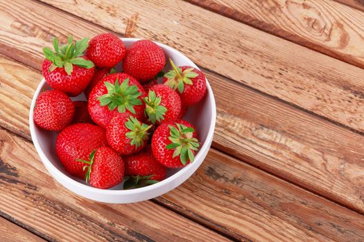 Strawberries in a saucer on a wooden background