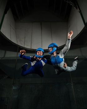 A man and a woman enjoy flying together in a wind tunnel. Free fall simulator.