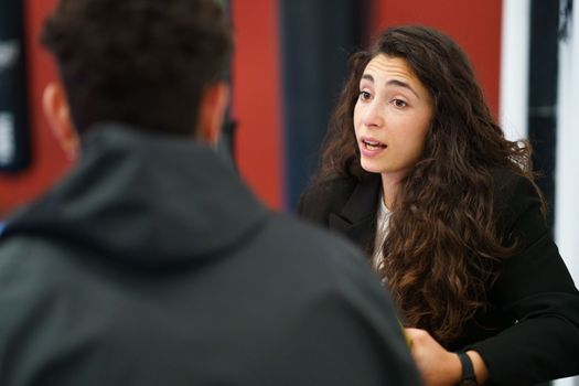 Young brunette talking with sportsman to improve performance during motivational therapy session in gym