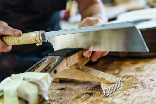 Spanish guitar maker, or luthier, working on a flamenco guitar. Unrecognizable craftsman marking the frets on the neck of a flamenco guitar, as part of the handcrafted manufacturing process.