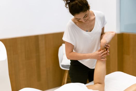 Middle-aged woman having a leg massage in a beauty salon. Body care treatment in a beauty centre.