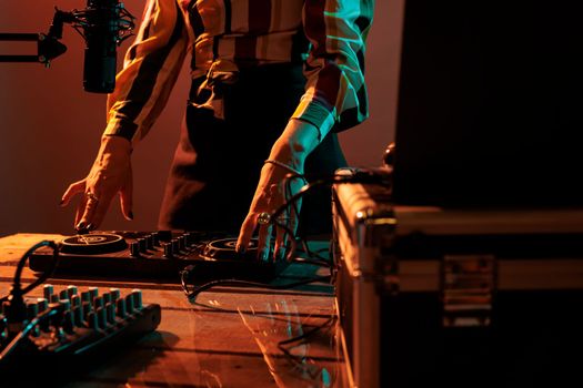 Woman artist using mixing turntables to play music at party, having fun with audio dj equipment for techno performance. Playing stereo sounds with electronics, microphone and headphones.