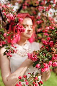 Blooming pink Apple. Apple trees bloom. Young girl with pink hair in Apple orchard. Selective focus.
