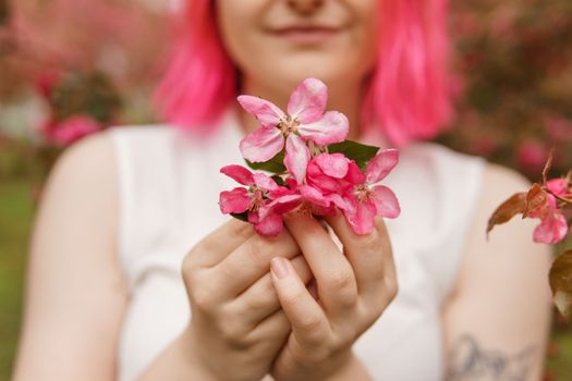 Blooming pink Apple. Apple trees bloom. Young girl with pink hair in Apple orchard. Selective focus.