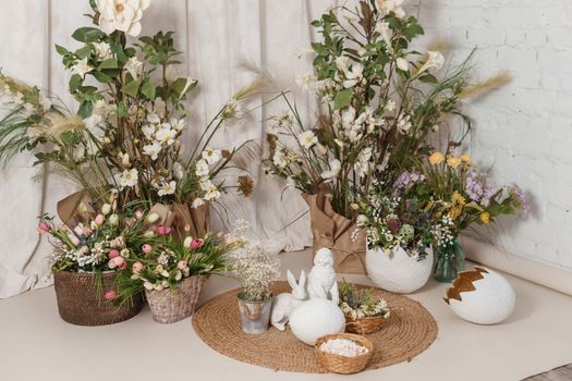 Interior floral Easter composition. Figurines of Easter bunnies and a large eggshell. The concept of home decoration for the Happy Easter holiday