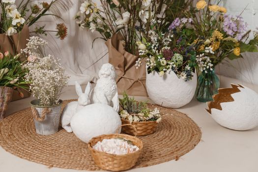 Interior floral Easter composition. Figurines of Easter bunnies and a large eggshell. The concept of home decoration for the Happy Easter holiday