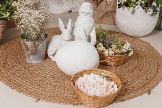 Interior floral Easter composition. Figurines of Easter bunnies and a large eggshell. The concept of home decoration for the Happy Easter holiday