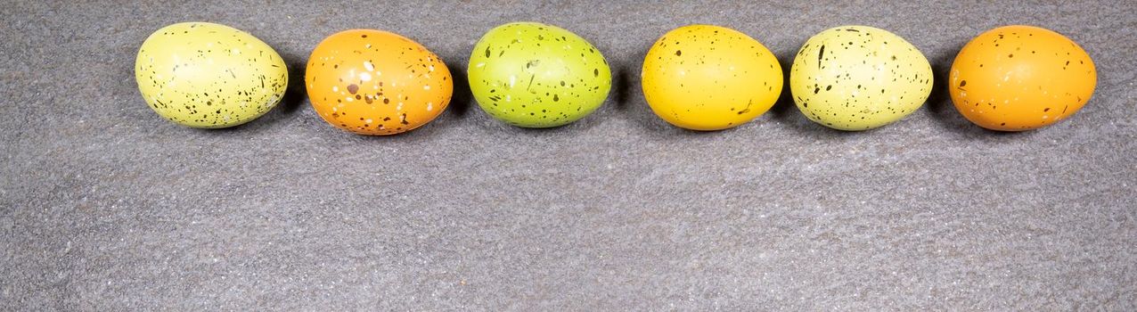 Mix of easter eggs of all colors and sizes on a gray granite stone background. Easter concept.