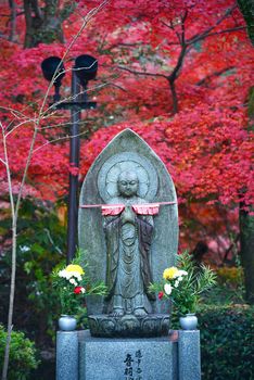 buddha statue with red maple leaves in japan