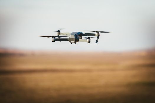 Drone flying in the sky over open fields for shooting video.