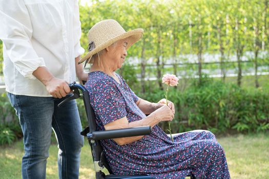 Caregiver help and care Asian senior or elderly old lady woman patient sitting and happy on wheelchair in park, healthy strong medical concept.